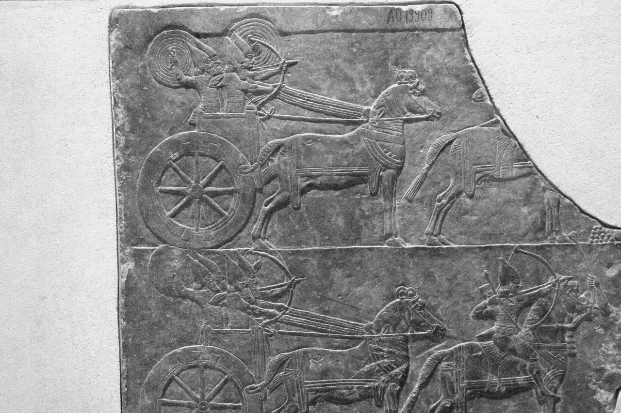 Stone carving of Mesopotamian chariots and archers in museum